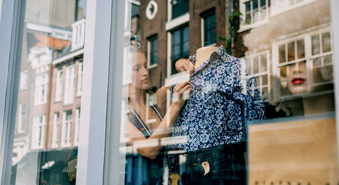 Visual merchandiser arranging a fashion window display